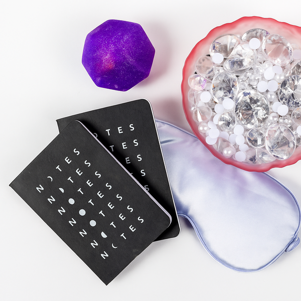 Black 'NOTES' packaging with a purple crystal, clear gemstone, and purple silicone product on a white background